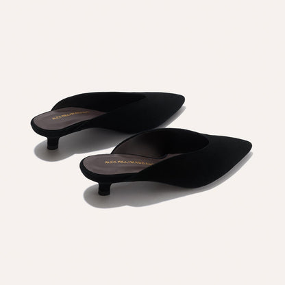 The Romy - Black Suede kitten mule heels by Margaux, from the Alex Mill x Margaux collection, feature pointed toes, black slip-on design, and gold branding on the insoles, displayed on a neutral background.