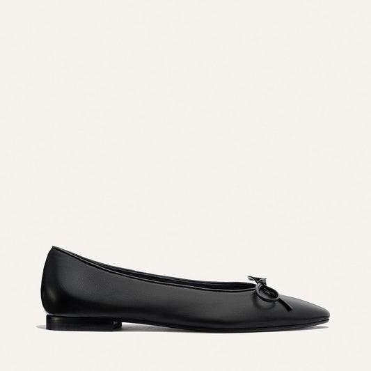 The Salamanca - Black Nappa by Margaux: a buttery soft black leather ballet flat with a small bow on the toe, shown in profile against a plain white background.