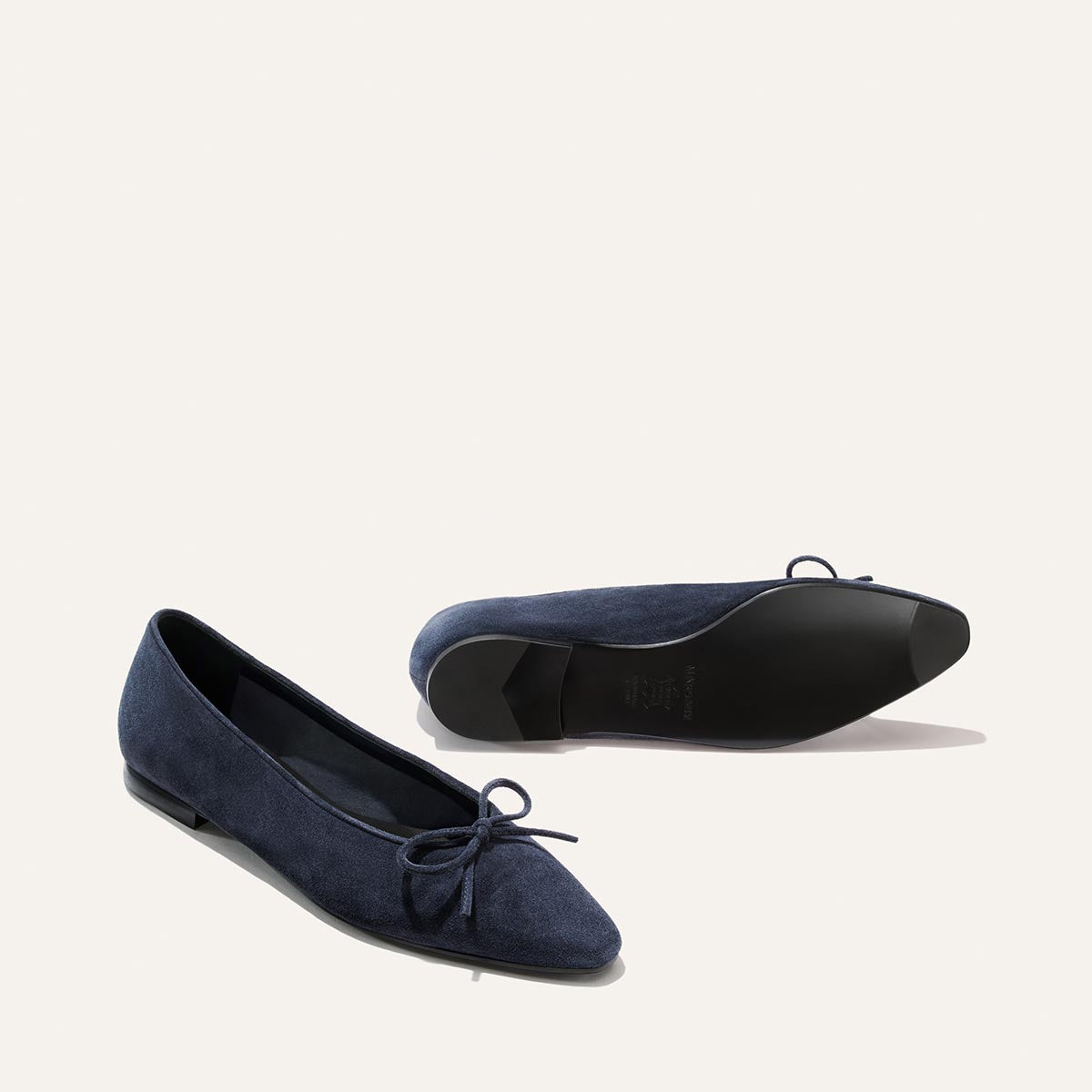 The Salamanca - Vintage Navy Suede pointed-toe flats with small bows, shown from the side and the bottom to highlight their unlined navy blue suede construction.