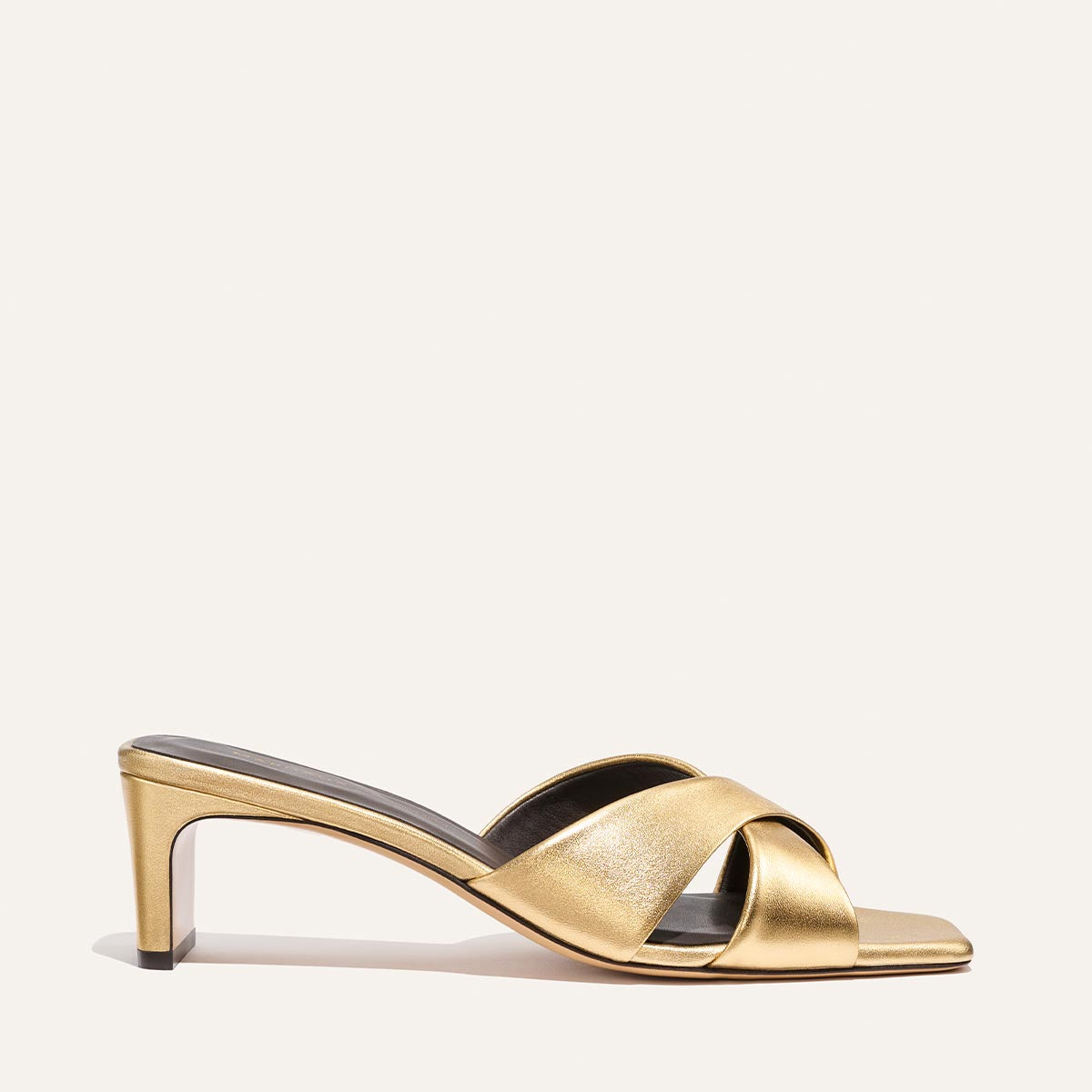 The Selene 50 - Gold Nappa by Margaux is a gold heeled sandal with crisscross leather straps, block heel, and open toe, shown on a plain, light background.