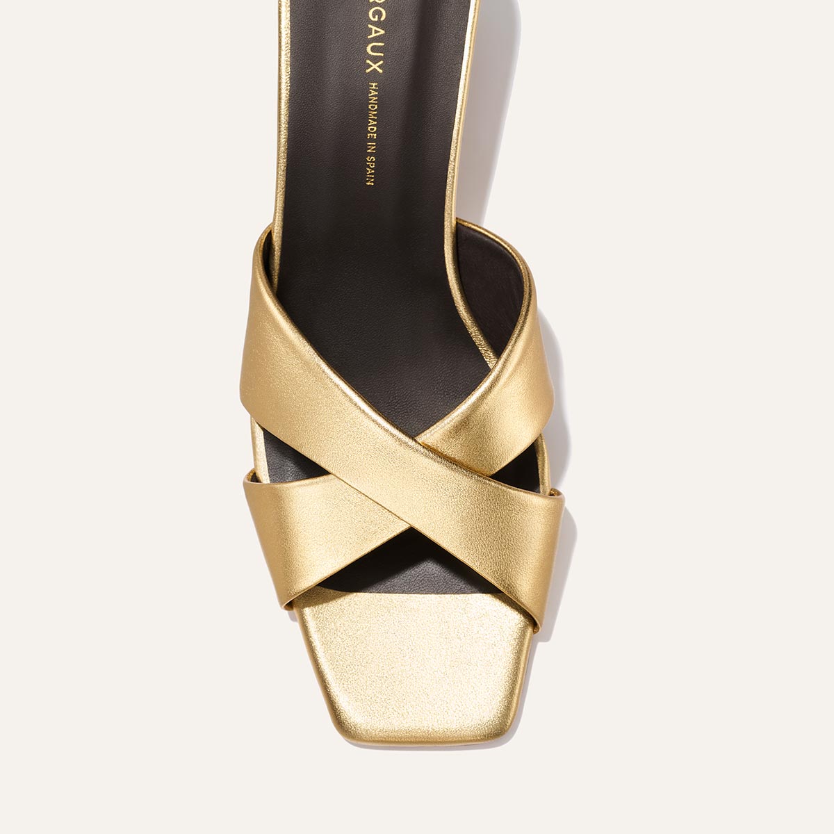 The Selene 50 - Gold Nappa by Margaux: a gold heeled sandal with wide leather crisscross straps and a square toe, shown from above on a light background. Features a black insole with gold Margaux branding.