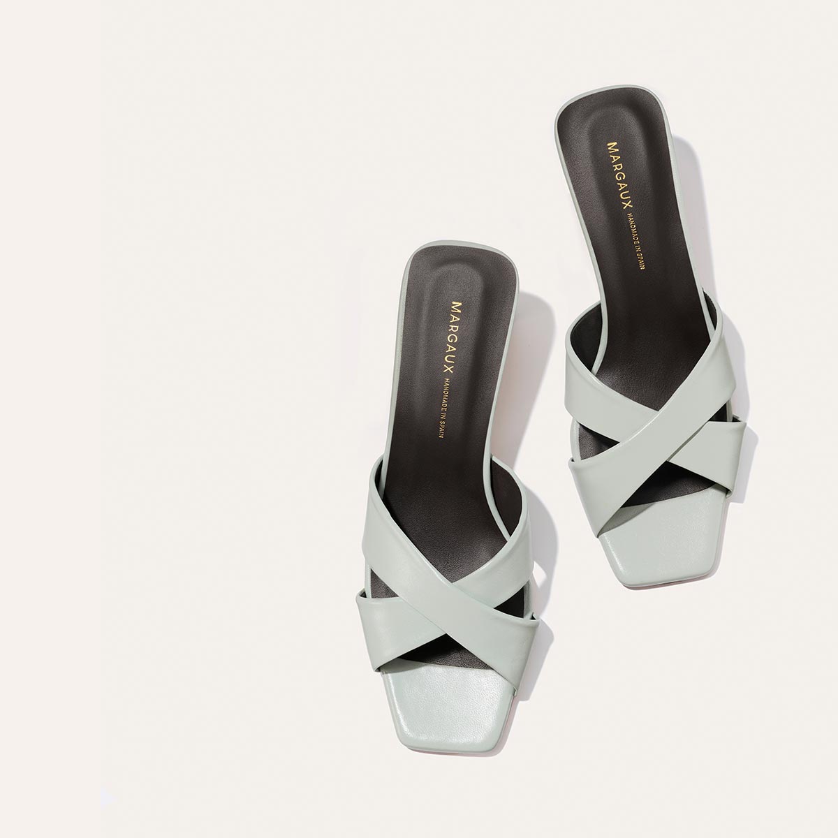 The Selene 50 - Sky Nappa light blue mule sandals featuring wide crisscross straps, a padded insole, and a low block heel.