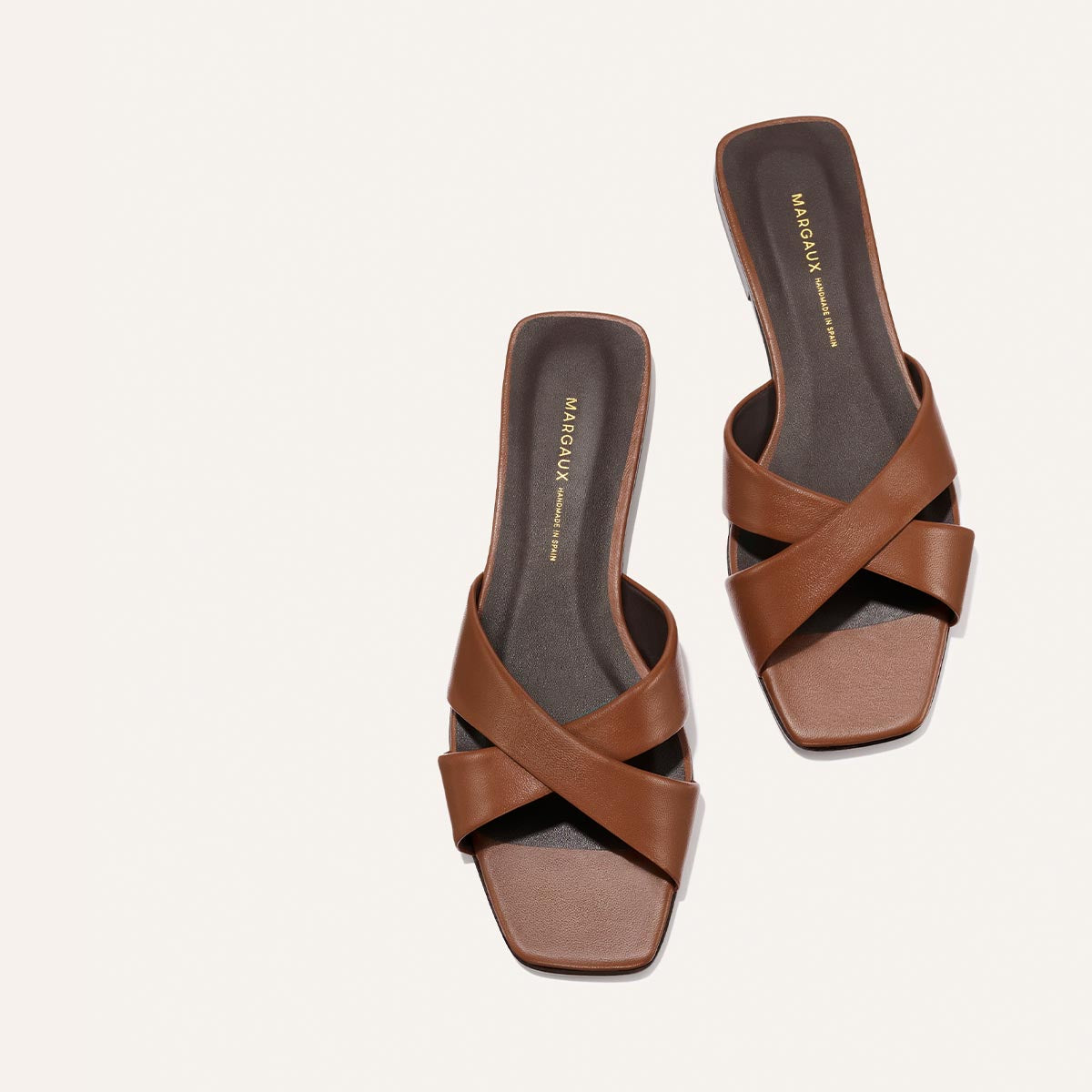 Pair of brown sandals with criss-cross straps on a white background