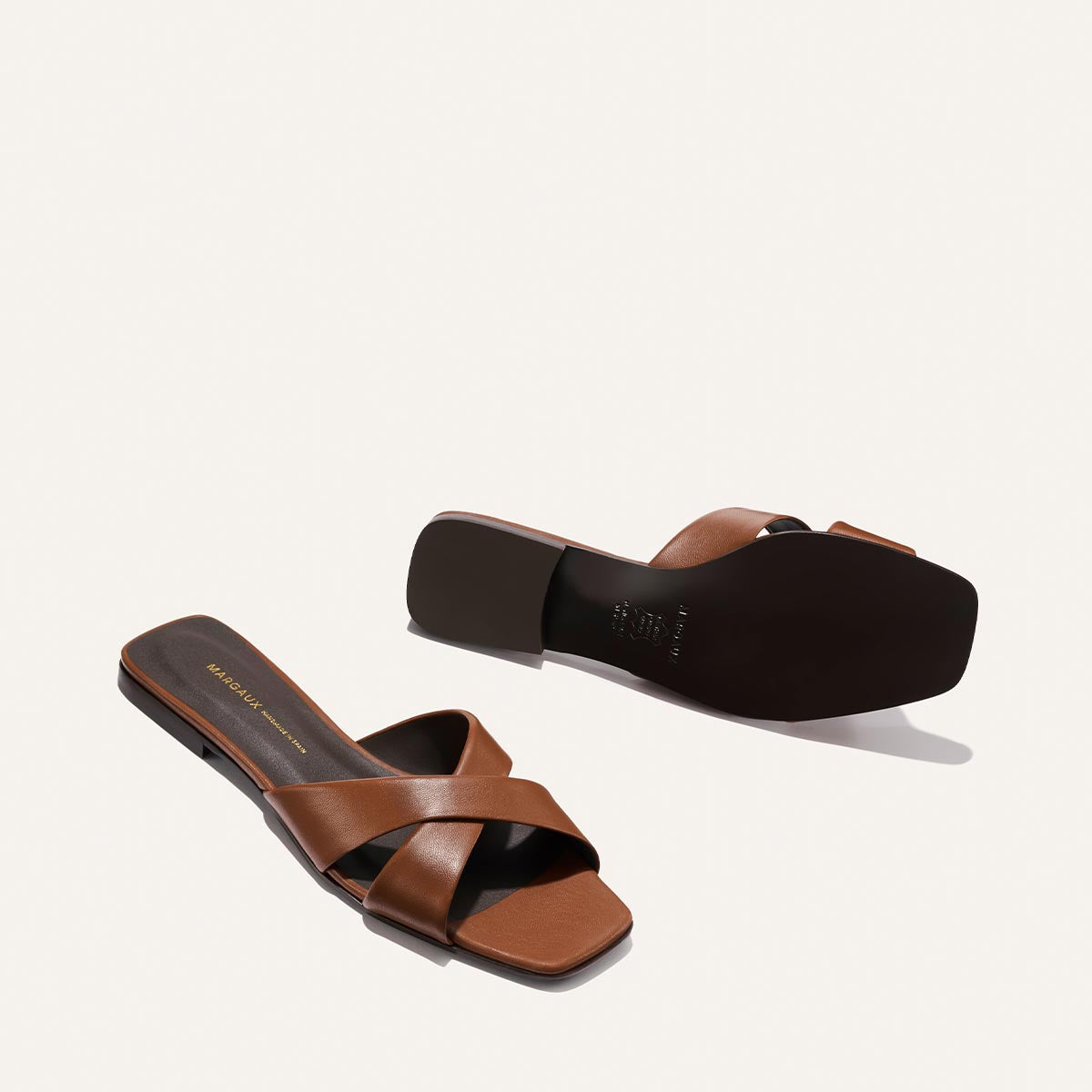 Pair of brown sandals on a light beige background