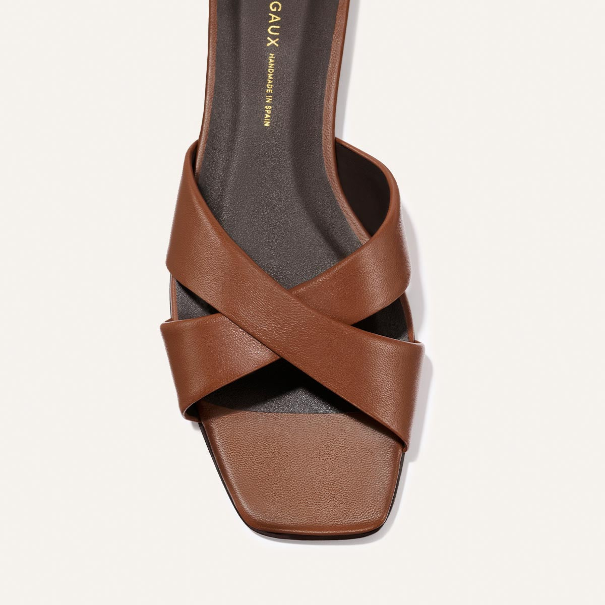 Brown sandal with criss-cross straps on a white background