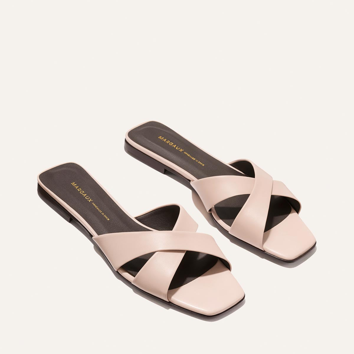Pair of pink sandals with criss-cross straps on a white background