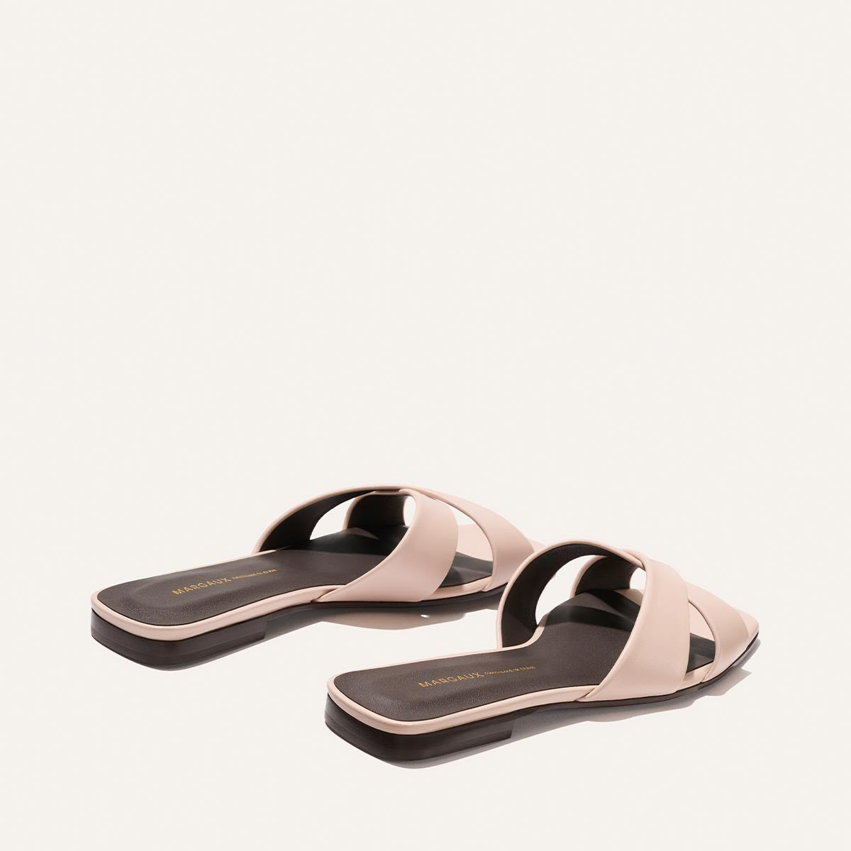 Pair of pink sandals with black soles on a white background