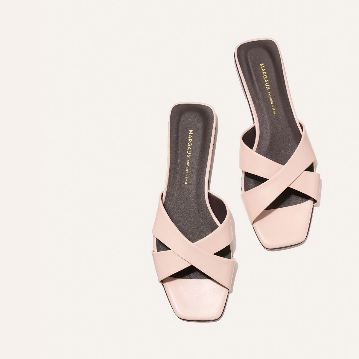 Pair of pink sandals with criss-cross design on a white background