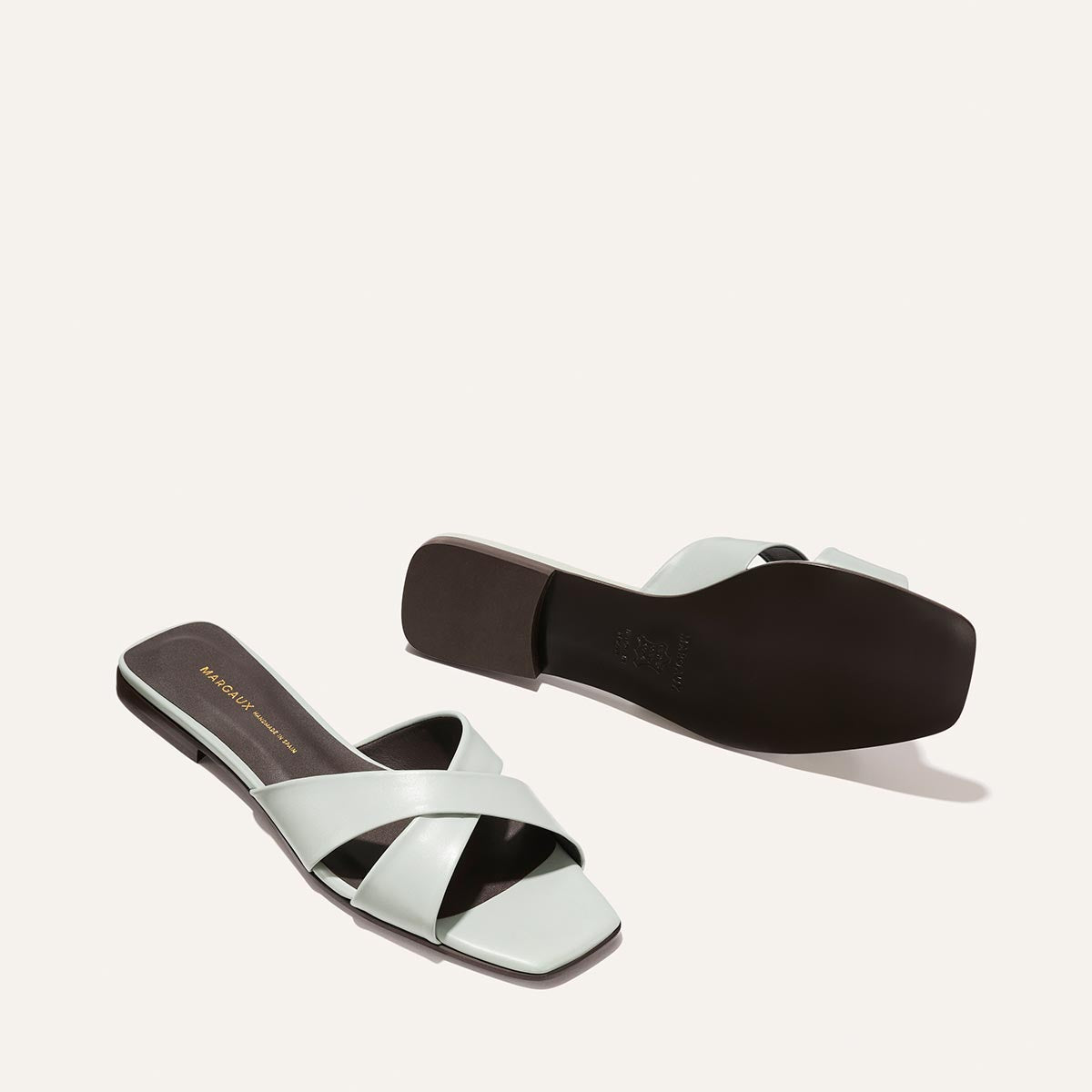 Pair of light blue sandals with black soles on a white background
