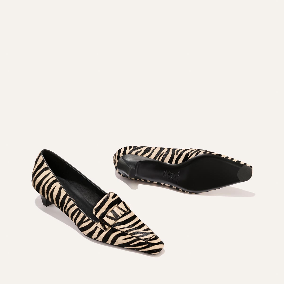 A pair of The Sigrid - Tan Zebra Haircalf low-heeled loafers with a tan and black zebra print pattern.