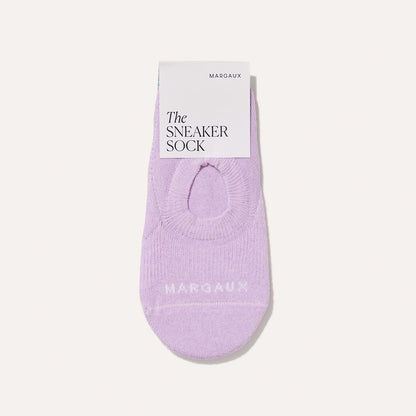 A single Margaux Sneaker Sock in Wisteria, a light purple no-show style, is neatly folded with a white tag labeled The SNEAKER SOCK, combining comfort and style against a plain background.