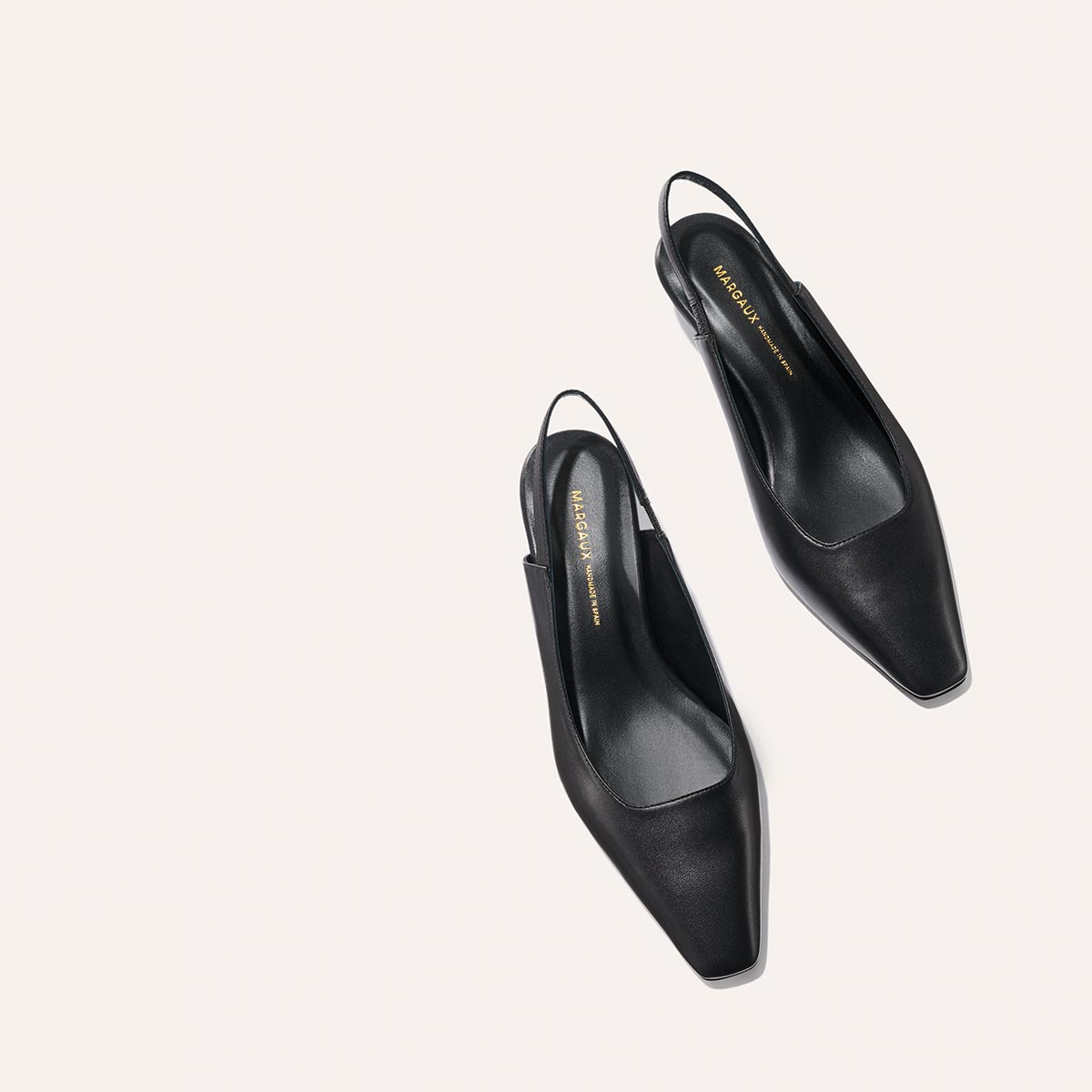 The Sofia Sling - Black Nappa by margaux-development: black snip-nose slingback heels with a low-cut front and branded insoles, displayed on a light, minimal background.