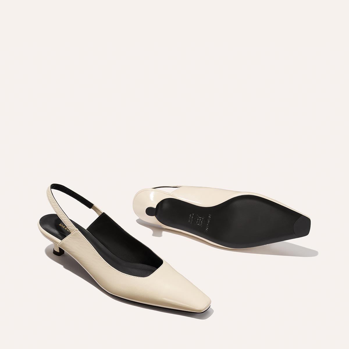 The Sofia Sling - Ecru Crinkle Patent by Margaux: cream-colored slingback kitten heels with black insoles, chic snip toes, shown upright and on their side to display the sole.