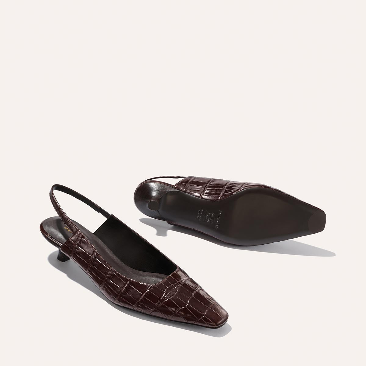 The Sofia Sling - Espresso Croc Embossed by Margaux: brown crocodile-embossed slingback shoes with low micro heels and pointed square toes, shown on a light background with one upright and one lying on its side.
