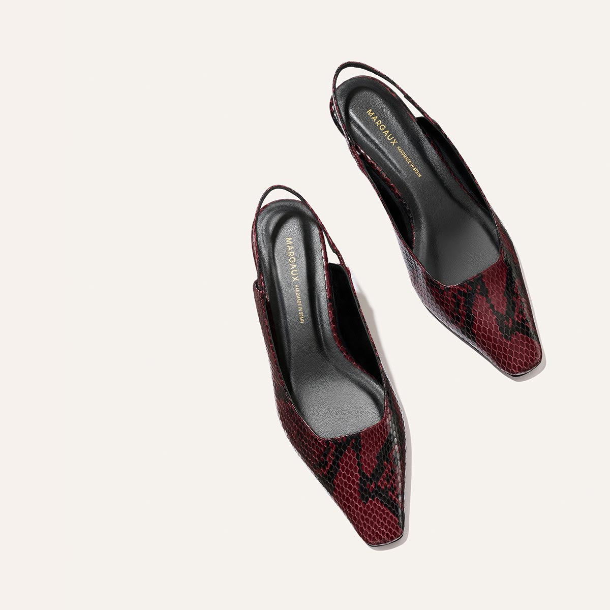 A pair of Margaux "The Sofia Sling" heels in burgundy python-embossed leather with pointed toes and black insoles featuring gold brand text, displayed on a light background.