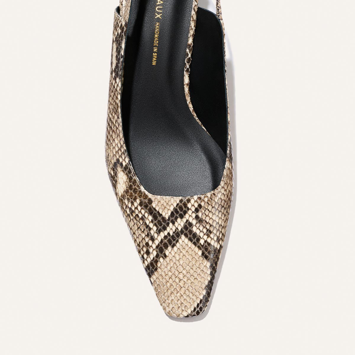 A close-up of The Sofia Sling by Margaux, showcasing its pointed toe and snip nose silhouette in a natural python-embossed beige and black pattern, finished with a sleek black insole and an elegant 1.5" heel.