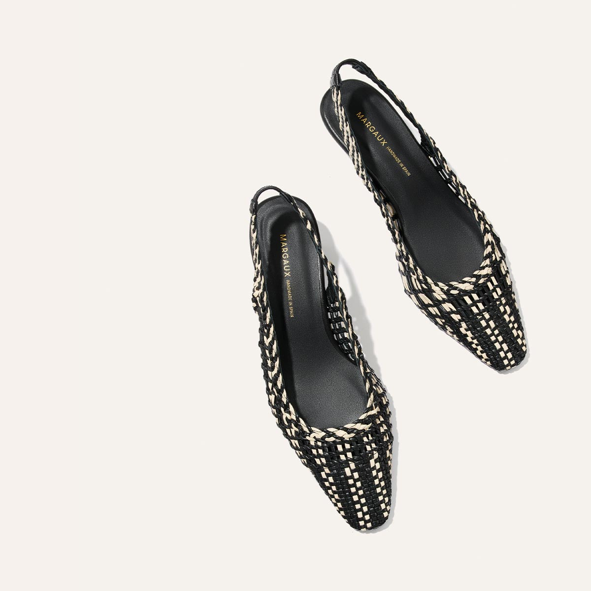Black and white woven slingback shoes on a light gray background