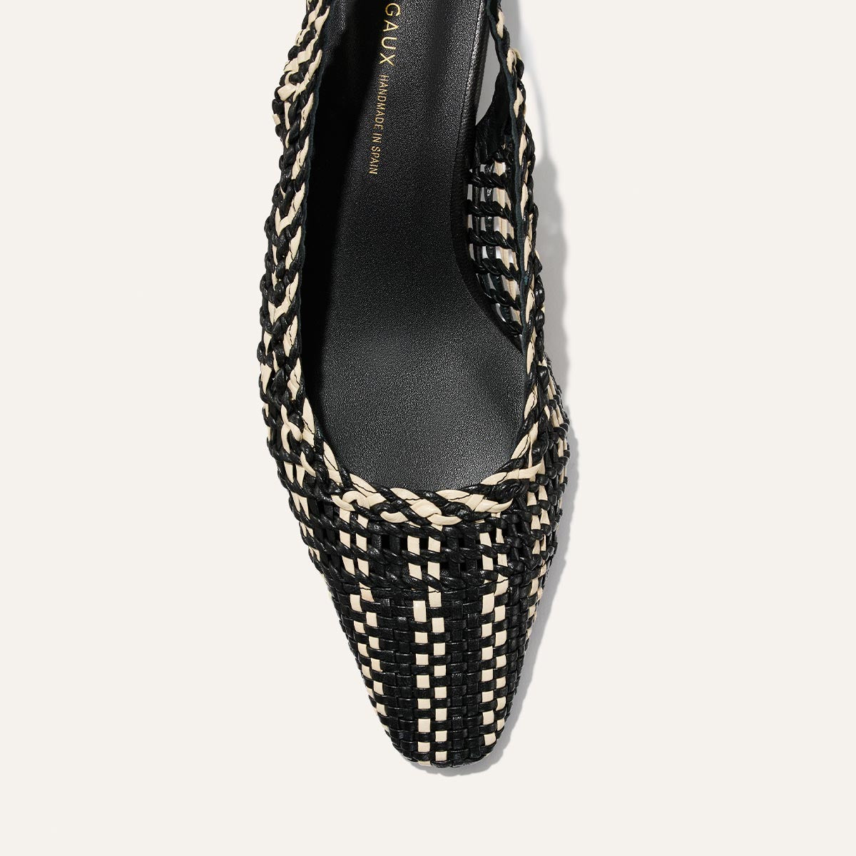 Black and beige woven shoe on a light gray background