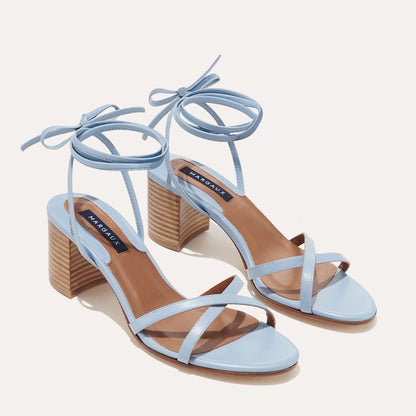 The Soho Sandal - Fog Nappa by margaux-development features light blue wrap design, crisscross straps, ankle ties, and chunky tan block heels—a summer staple—shown on a neutral background.