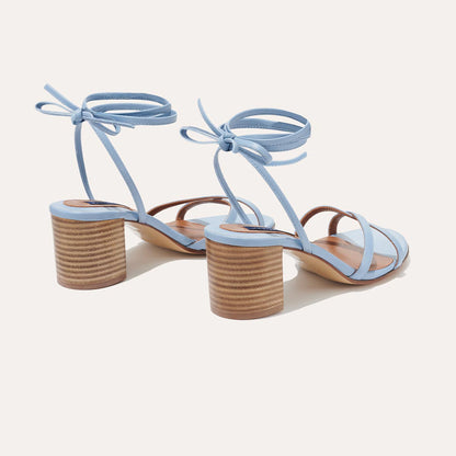 The Soho Sandal - Fog Nappa by margaux-development features light blue open-toe wrap design, ankle straps tied in bows, and medium block heels—an effortless summer staple styled against a light background.