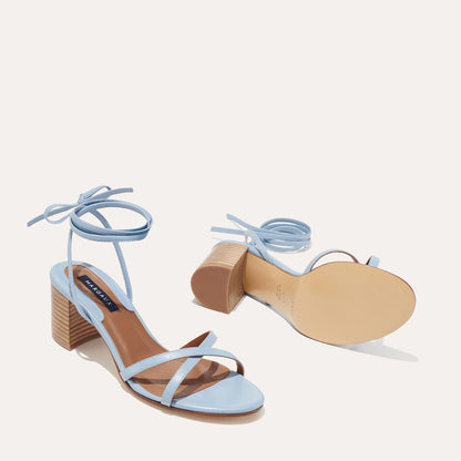 The Soho Sandal - Fog Nappa by margaux-development: light blue, open-toe block heel sandals with ankle straps and a tie closure—perfect summer shoes. One sandal stands upright; the other lies on its side, showing the sole.
