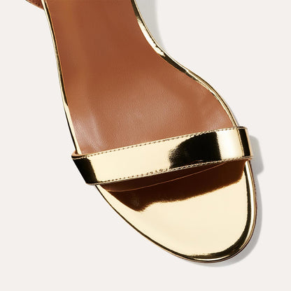 The Stella Sandal in shiny Gold Mirror, featuring a sleek strap across the toes and a comfortable 2.5-inch breasted heel.