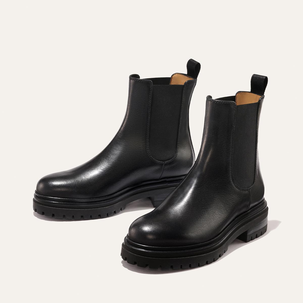 The West Chelsea Boot - Black Calf by margaux-development features chunky lug soles, elastic side panels, and back pull tabs, shown in black on a light background.
