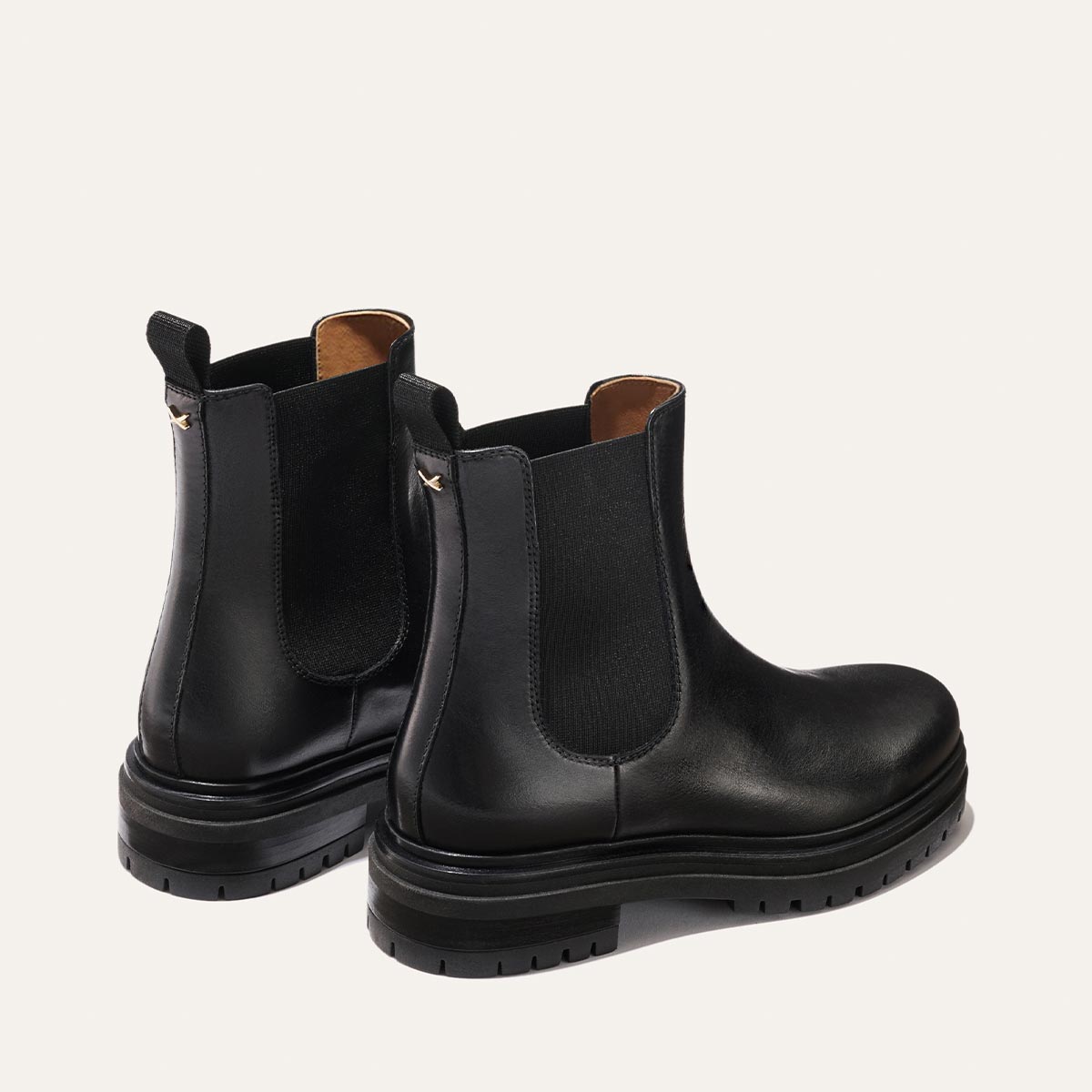 The West Chelsea Boot - Black Calf by margaux-development: black leather boots with elastic side panels, back pull tabs, and thick lug soles for grip, shown on a plain light background.