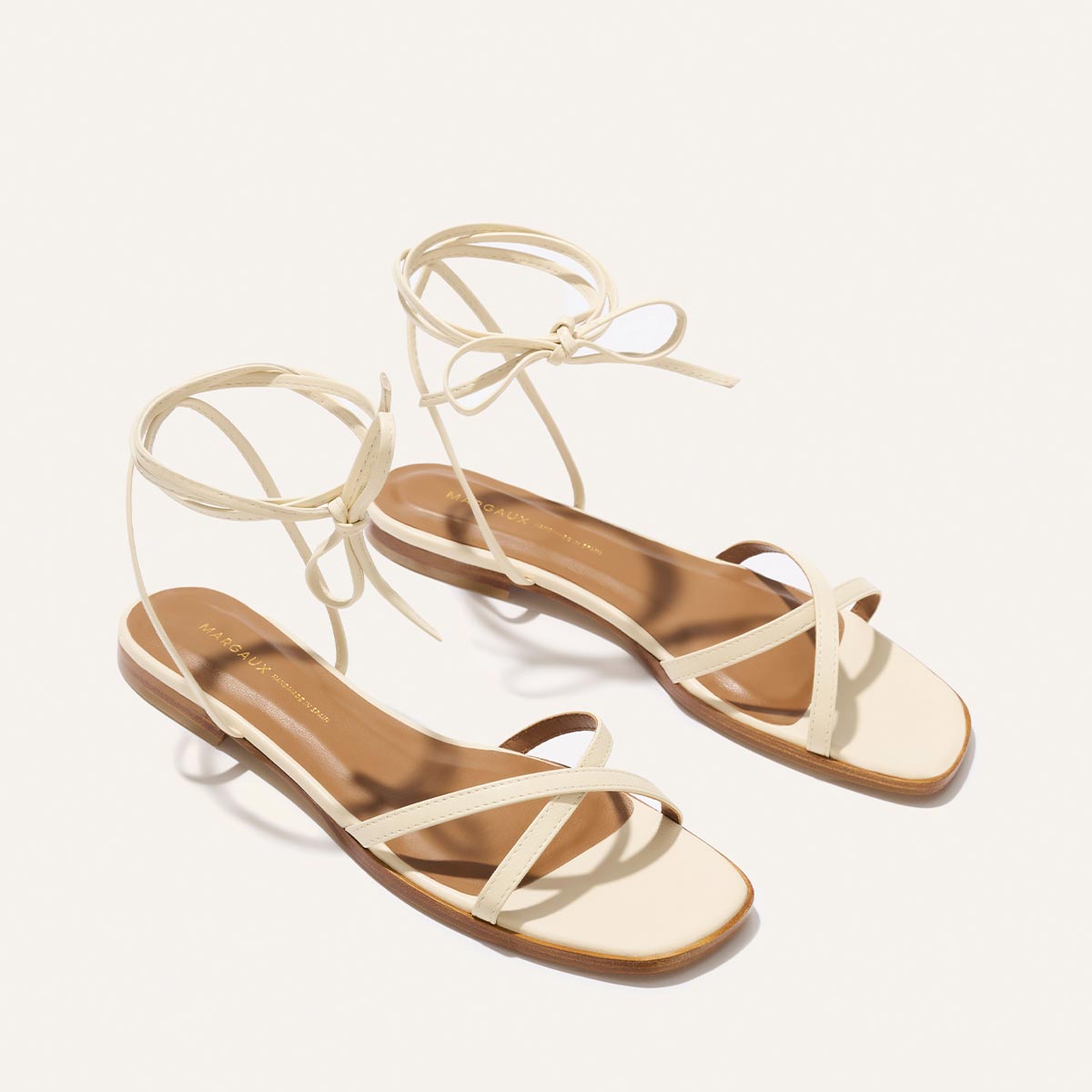 Pair of strappy sandals with beige straps on a white background