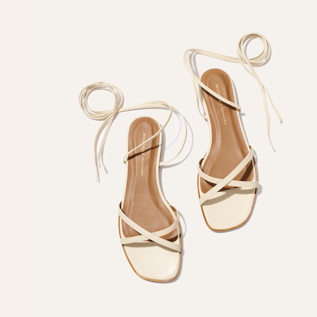Pair of strappy sandals with beige straps on a white background