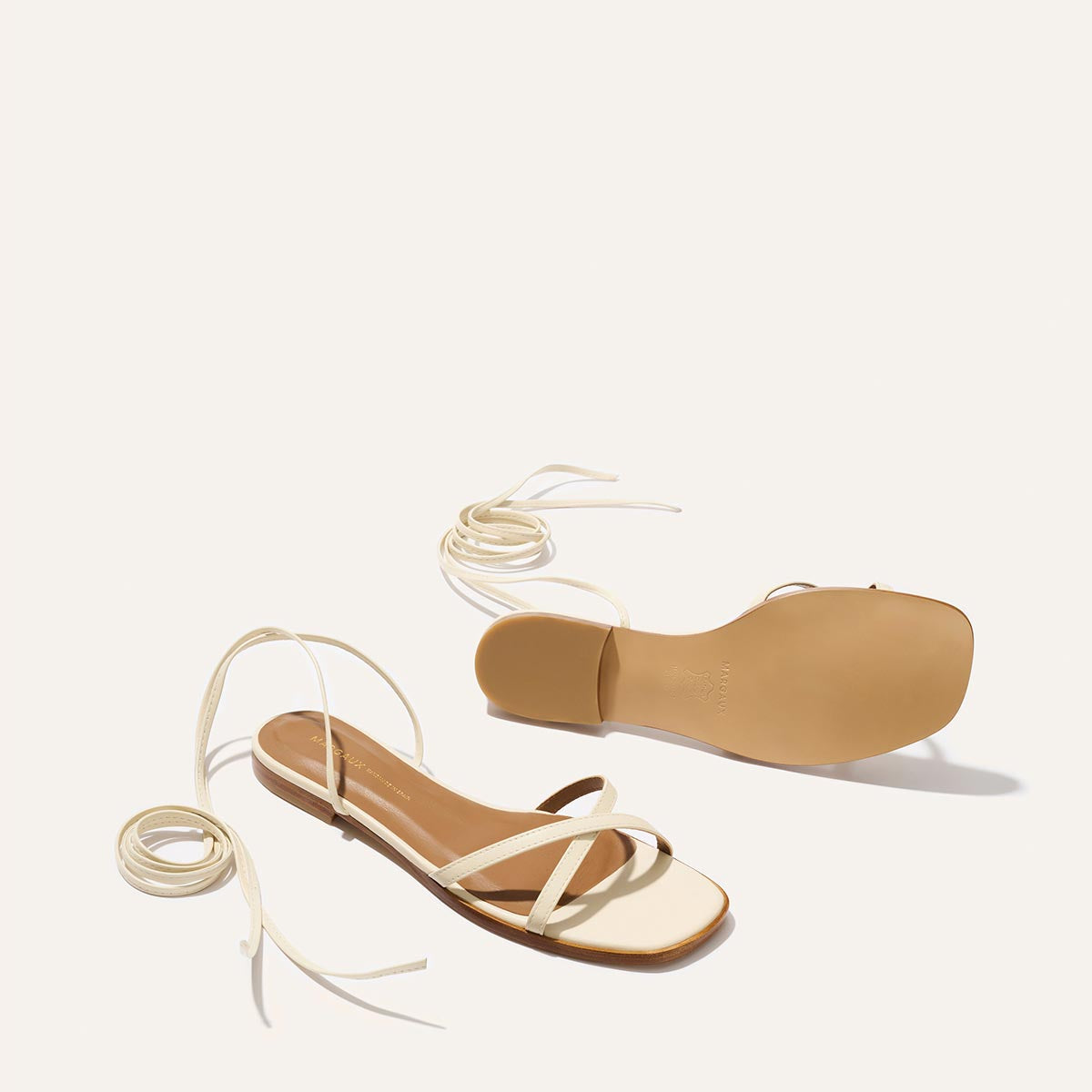 Pair of strappy sandals with beige straps on a white background