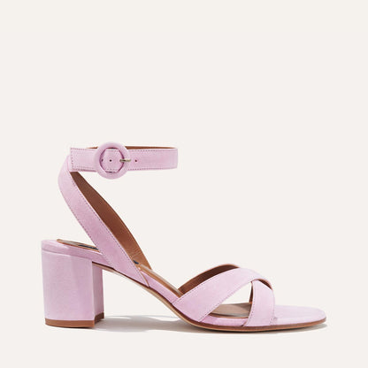 The City Sandal - Wisteria Suede by margaux-development features a light pink suede, chunky block heel, crisscross toe straps, and a round-buckle ankle strap with a cushioned insole. Displayed on a plain, light background.