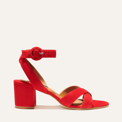 The City Sandal - Poppy Suede by margaux-development features vibrant red suede, a chunky block heel, crisscross toe straps, and a large round-buckle ankle strap. Designed for comfort with a cushioned insole, displayed on a neutral background.