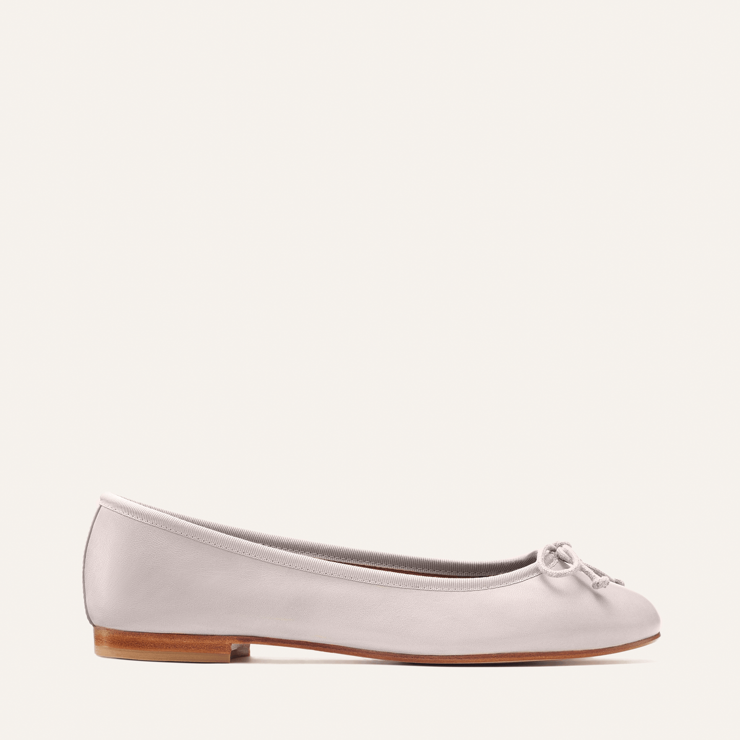 The Demi - Dove Nappa by margaux-development is a handmade light gray ballet flat from Spain, featuring a small front bow, low wooden heel, and classic design, shown against a plain off-white background.