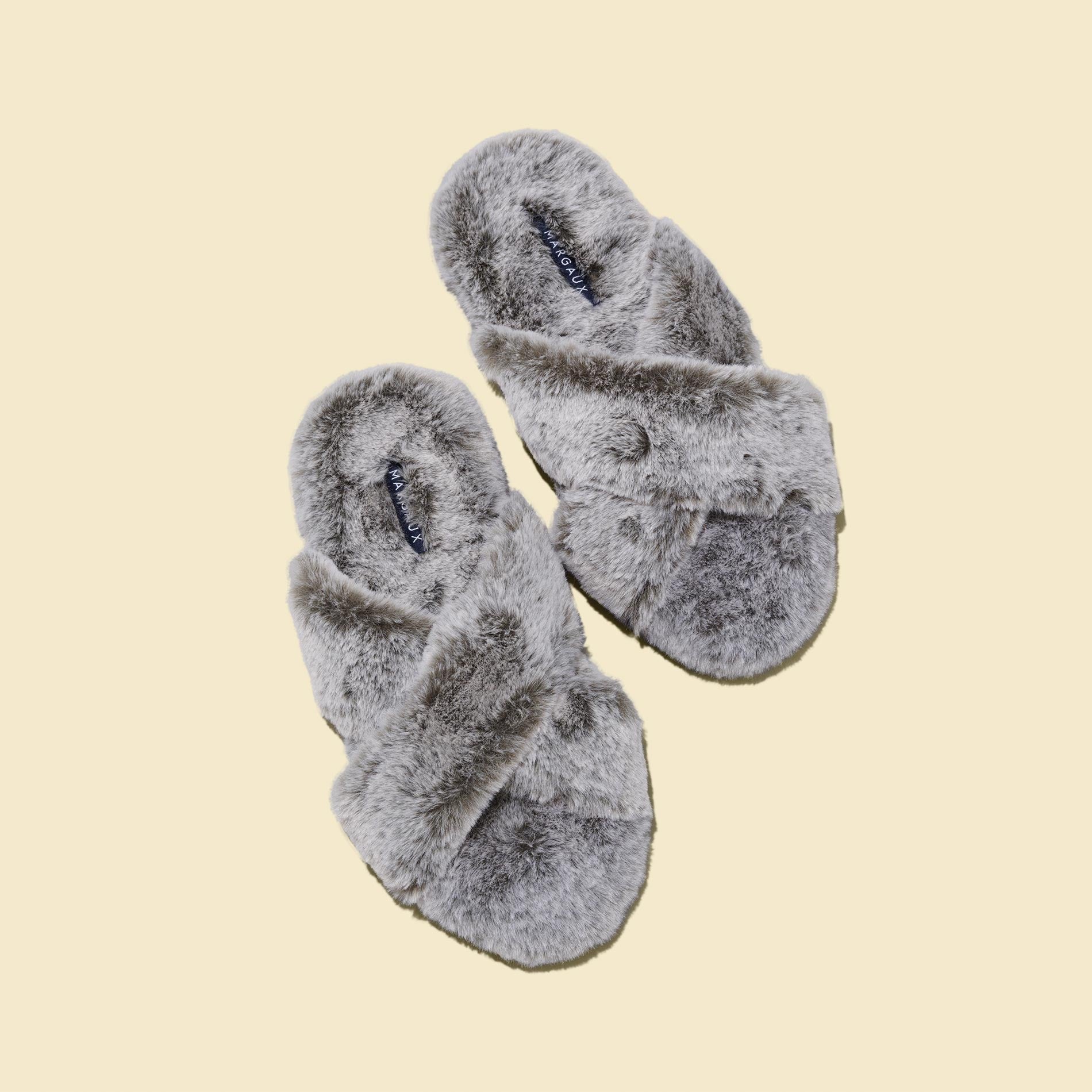 The Cozy Slipper - Grey by Margaux features a fluffy, x-strap design with open toes and is shown on a beige background.
