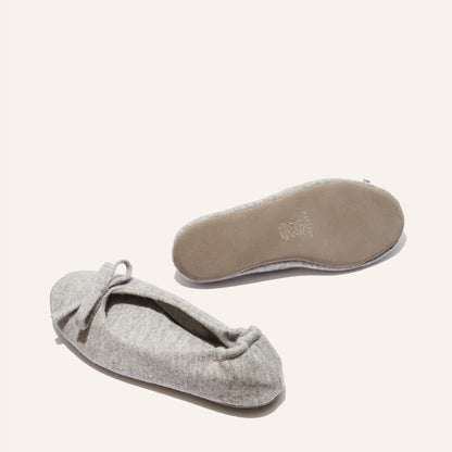 A pair of Margaux’s The Ballet Slipper - Heather flats, light gray wool-cashmere, one showing a bow-accented top and the other its tan sole—cozy archive-sale essentials against an off-white background.