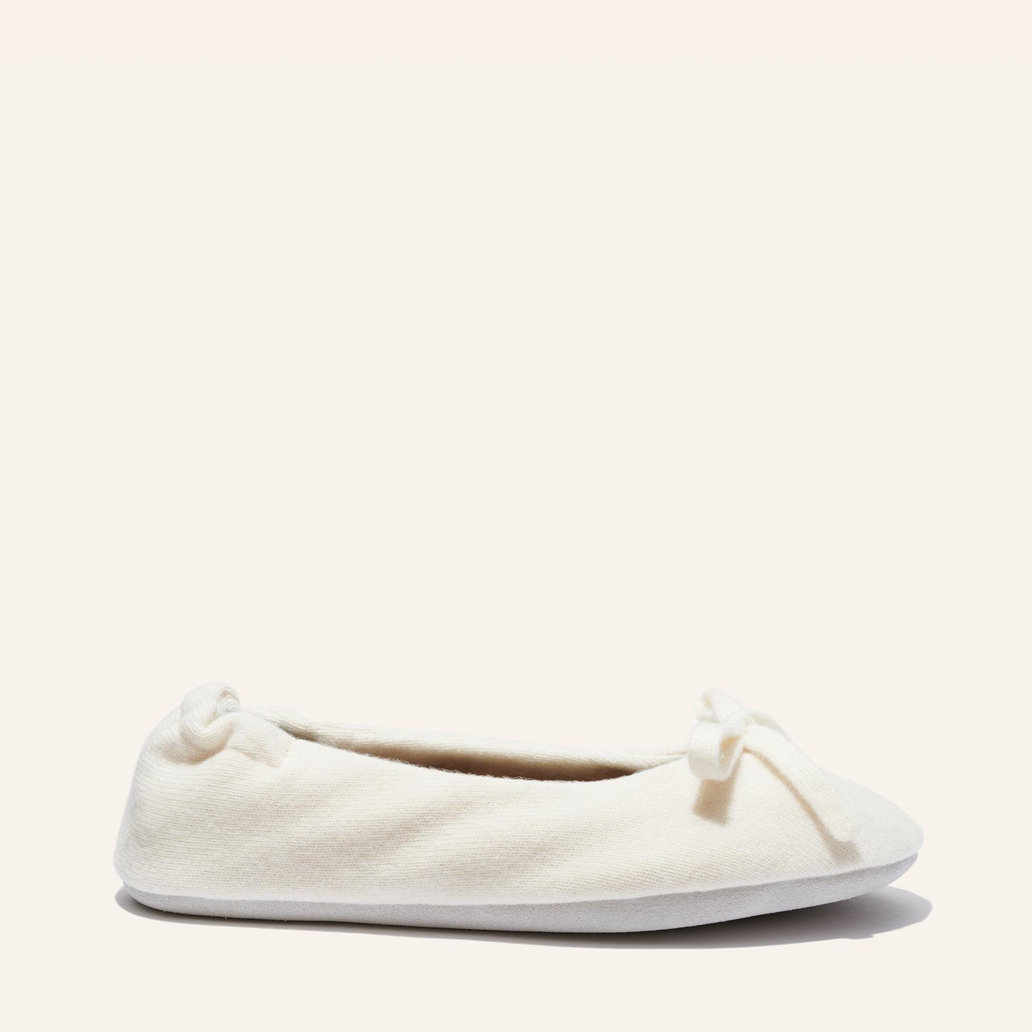 The Ballet Slipper - Ivory by Margaux is a cozy cream wool-cashmere ballerina flat featuring a small bow, shown in side view against a plain light background.