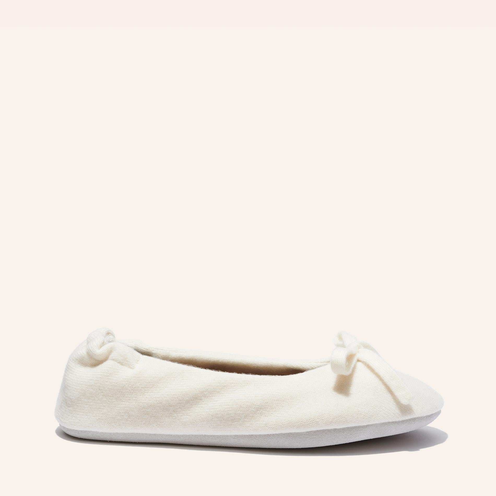 The Ballet Slipper - Ivory by Margaux is a cozy cream wool-cashmere ballerina flat featuring a small bow, shown in side view against a plain light background.