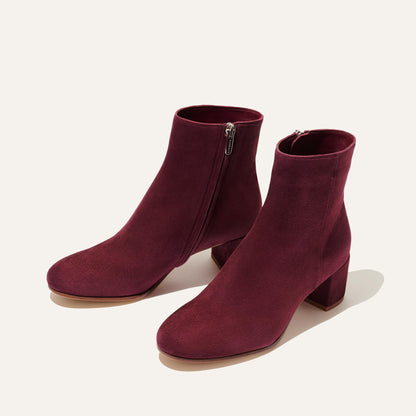 The Boot - Mulberry Suede by Margaux features a stylish almond-toe design, side zippers, and chunky low heels in rich burgundy suede, showcased on a light background.