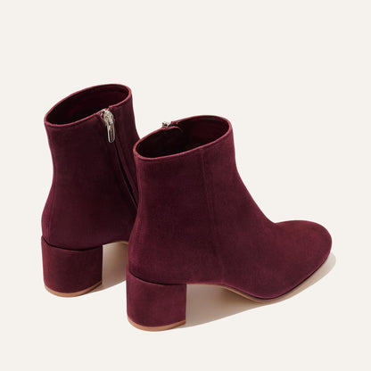 The Boot - Mulberry Suede by Margaux: a pair of burgundy suede almond-toe boots with chunky mid-height heels and side zippers, shown on a light background.