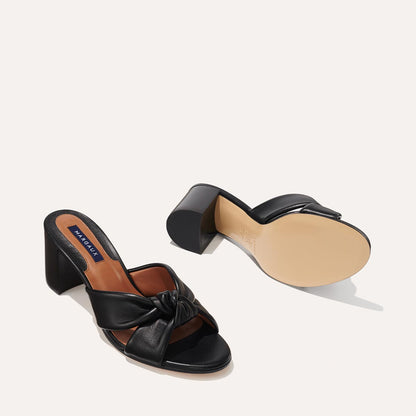 The Carmine Mule in Black Nappa, a slide-on heel featuring a plush knot detail and comfortable 2.5-inch block heel