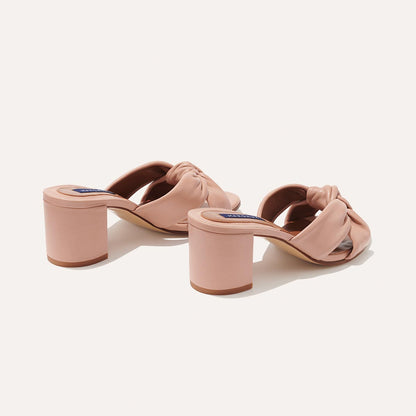 The Carmine Mule - Rose Nappa by margaux-development features blush pink heeled sandals with plush knot details, chunky block heels, and twisted straps for comfort and style.