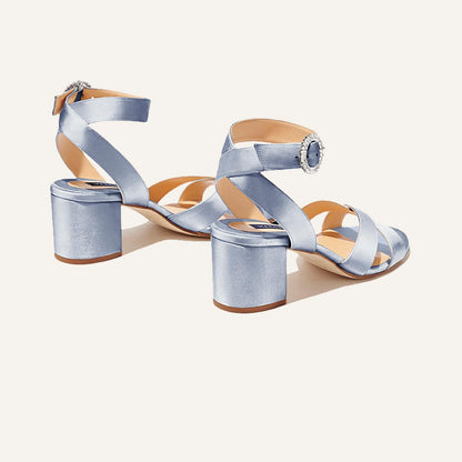 The City Sandal by margaux-development in powder satin features an open-toe heel, ankle strap, crystal buckle detail, and cushioned insole for comfort, shown against a plain light background.