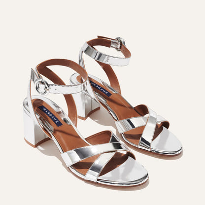 The City Sandal - Silver Mirror by margaux-development features shiny silver crisscross straps, ankle support, block heels, and tan insoles for all-day comfort.