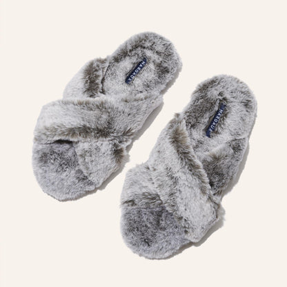 The Cozy Slipper - Grey by Margaux features a soft, fluffy texture and cozy x-strap design. This stylish faux fur slipper is displayed on a plain light background.