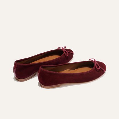 The Demi - Mulberry Suede by margaux-development: bestselling ballet flats handmade in Spain from burgundy suede, with rounded toes and pink bows, shown on a plain light background.