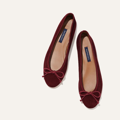 A pair of The Demi - Mulberry Suede ballet flats by margaux-development, shown from above on a light background. They feature matching bows, tan insoles with navy blue MARGAUX labels, and deliver exceptional comfort and style.