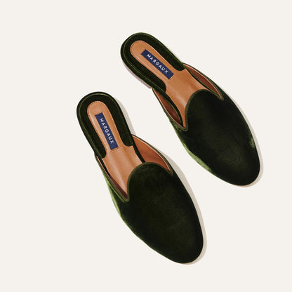 A pair of The Loafer Mule - Olive Velvet shoes by Margaux, featuring almond toes and tan insoles with Margaux branding, displayed on a plain light background.