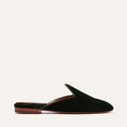 The Loafer Mule - Olive Velvet by Margaux features dark green velvet, a pointed toe, and a low brown heel, shown against a light background.