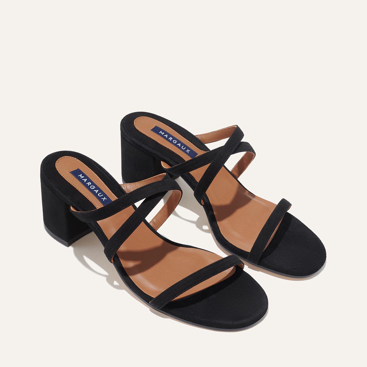 The Perry Sandal - Black Suede by margaux-development: black, open-toe block heel sandals with a suede upper, three slim foot straps, tan insoles featuring Margaux branding, shown on a neutral background.